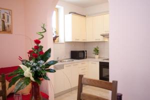 a kitchen with white cabinets and a vase of flowers at Apartments Beautiful Sandy Beach in Split