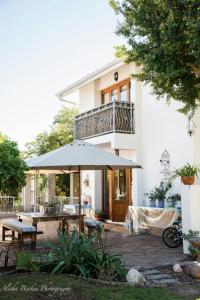 ein Haus mit einem Tisch und einem Sonnenschirm davor in der Unterkunft Cobie Apartment in Stellenbosch