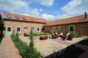 a patio with couches and chairs in front of a brick building at Holtby Grange Cottages in York