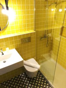 a yellow tiled bathroom with a toilet and a shower at Lemon Tree Apartments in Faro