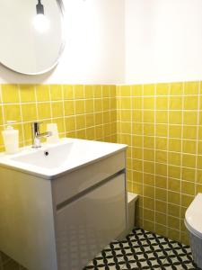 a bathroom with a sink and yellow tiles at Lemon Tree Apartments in Faro