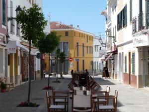 una strada vuota con tavoli e sedie in una città di Sa Lluna a Es Mercadal