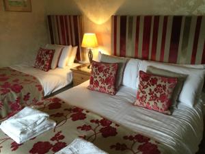 a hotel room with two beds with red and white pillows at Craigroyston House in Pitlochry