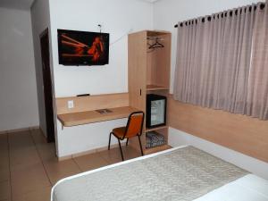 a bedroom with a bed and a desk with a computer at Hotel Lider - Catanduva in Catanduva