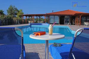 a table with a drink on it next to a swimming pool at Monachus Monachus in Frangokastello