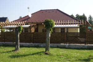 dos árboles frente a una casa con una valla en Mesteri Apartman 1A-B, en Mesteri