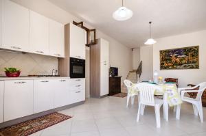 cocina con armarios blancos, mesa y sillas en Casale Dei Gelsi, en Castellammare del Golfo