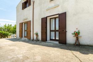 un edificio blanco con puertas de madera y flores en una mesa en Casale Dei Gelsi, en Castellammare del Golfo