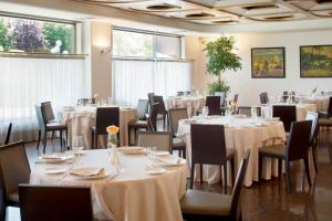 une salle à manger avec des tables, des chaises et un tissu de table blanc dans l'établissement Starhotels Cristallo Palace, à Bergame