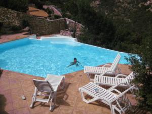 ポルト・チェルボにあるResidence Pevero Hill Porto Cervoの(椅子付きのスイミングプールで泳いでいる)