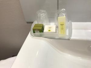 a white toilet in a bathroom with someentedented products on it at LOGIS Hotel-Restaurant Le Relais d'Aligre in Châteauneuf-en-Thymerais +70 photos