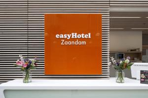 two vases of flowers on a counter with an orange sign at easyHotel Amsterdam Zaandam in Zaandam