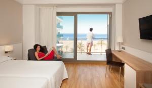 a woman sitting in a chair in a hotel room with the ocean at RH Bayren Hotel & Spa 4* Sup in Gandía