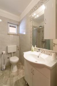 a bathroom with a white sink and a toilet at Apartments Robi in Trogir +63 photos