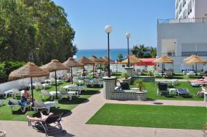 a patio with chairs and umbrellas and the ocean at First Flatotel International in Benalmádena