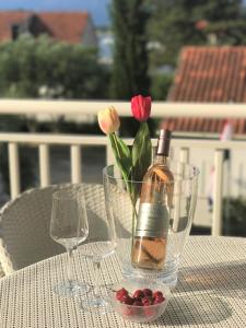 uma garrafa de vinho e flores sobre uma mesa em Apartmani Fortuna em Lumbarda