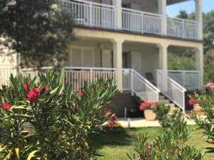 uma casa com flores cor-de-rosa em frente em Apartmani Fortuna em Lumbarda