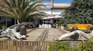 a wooden deck with palm trees and furniture and a building at Levolle Marine in Poggio-Mezzana
