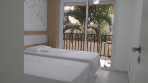 a bedroom with a bed and a balcony with a palm tree at Beach Living 1111 in Aquiraz
