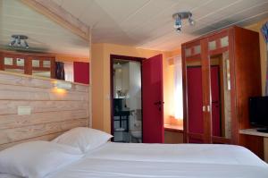 a bedroom with a white bed and a bathroom at Hotel Les Arcades in La Roche-en-Ardenne