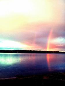 a rainbow in the sky over a large body of water at Marble Lake Lodge in Cloyne