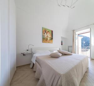a white bedroom with two beds and a window at Casa Rosanna in Maiori