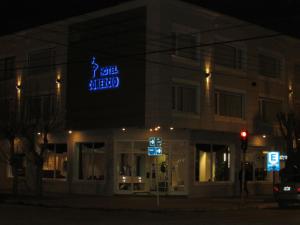 a building with a neon sign on the side of it at Hotel Comercio in Río Gallegos