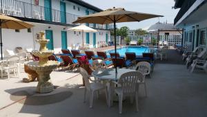 a patio with tables and chairs and a fountain at The Amethyst Beach Motel in Point Pleasant Beach