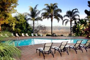 eine Gruppe von Stühlen, die um einen Pool herum sitzen in der Unterkunft Pacific Palms Resort and Golf Club in La Puente