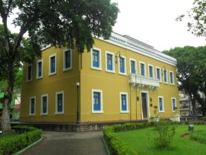 a yellow building with blue windows in a park at Hotel Pirahy in Piraí