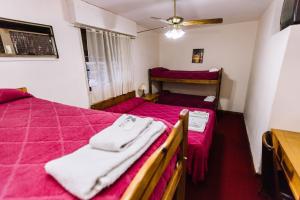 a bedroom with two beds with pink sheets and white towels at Avenida Hotel in Junín