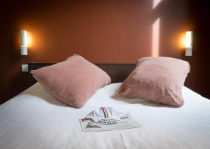 a bed with two pink pillows and a book on it at Hotel Marcel in Bruges