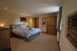 a bedroom with a bed and a stone wall at Lakeview Cottage in Callington