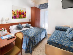 カットーリカにあるHotel Caesarのベッド2台とデスクが備わるホテルルームです。