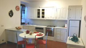Caniparola di FosdinovoにあるChiara Apartmentのキッチン(白いキャビネット、テーブル、椅子付)