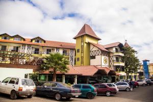 a large yellow building with cars parked in front of it at Hotel Kirst in Piratuba