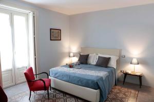 1 dormitorio con 1 cama y 1 silla roja en Agrumè Country House, en Santa Venerina