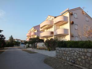 a large apartment building with a stone wall next to a street at Apartment Jurja in Povljana