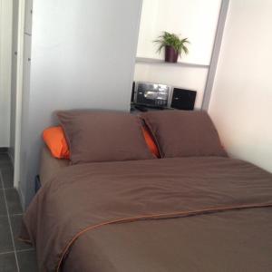 a bed in a small room with an orange pillow at K&A Apartment in Aulnay-sous-Bois