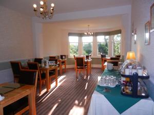 a dining room with tables and chairs and windows at Overcombe House in Yelverton