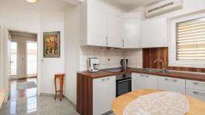a kitchen with white cabinets and a wooden table at House Coko in Baška Voda