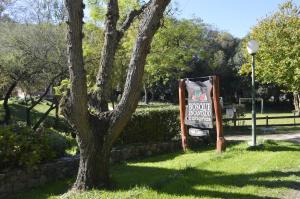 a sign sitting next to a tree in a park at Cabañas Bosque Encantado in Merlo