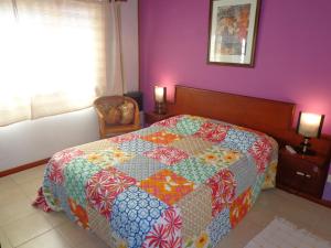 Un dormitorio con una cama con una colcha colorida. en Villa Olimpia Cabañas en Villa Gesell