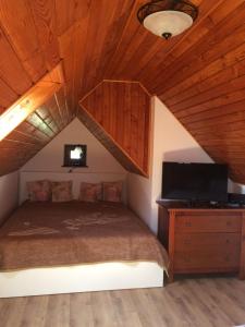 1 dormitorio con cama, TV y techo de madera en Vörösmál Vendégház, en Balatonfüred