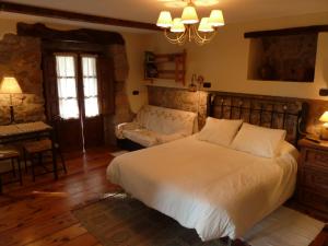 a bedroom with a large white bed and a couch at Casa Rural La Cortina in Pandiello