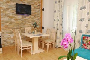 una sala da pranzo con tavolo, sedie e TV di Apartments Kuc a Tivat