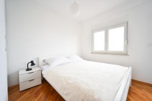ein weißes Schlafzimmer mit einem Bett und einem Fenster in der Unterkunft Apartments Dream in Nin