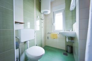 a white bathroom with a toilet and a sink at Apartments Dream in Nin +14 photos