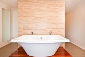a white bath tub in a bathroom with a mirror at Captains at the Bay in Apollo Bay