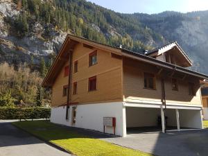 a large brown and white building with a mountain in the background at Family Frame Apartment in Lauterbrunnen